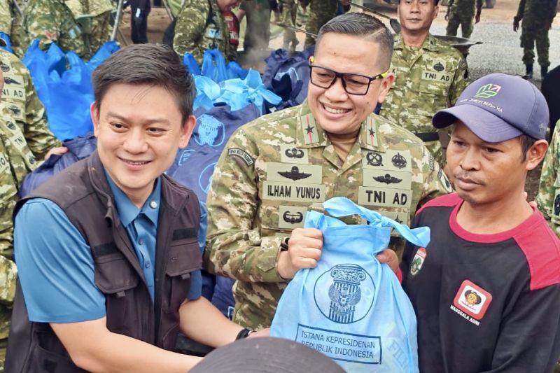 Danrem 101/Antasari Brigjen TNI Ilham Yunus (tengah) didampingi konten kreator Bobon Santoso (kiri) menyalurkan bantuan paket dari Presiden Prabowo kepada relawan pemadam karhutla pada kegiatan masak Kuali Merah Putih yang menyiapkan ribuan porsi makanan bagi relawan karhutla di Banjarbaru, Kalimantan Selatan, Senin (26/10/2026). (Foto-ANTARA/HO-Pemprov Kalsel)